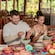 Two Guests sitting at a table and adding ingredients into a molcajete for mixing